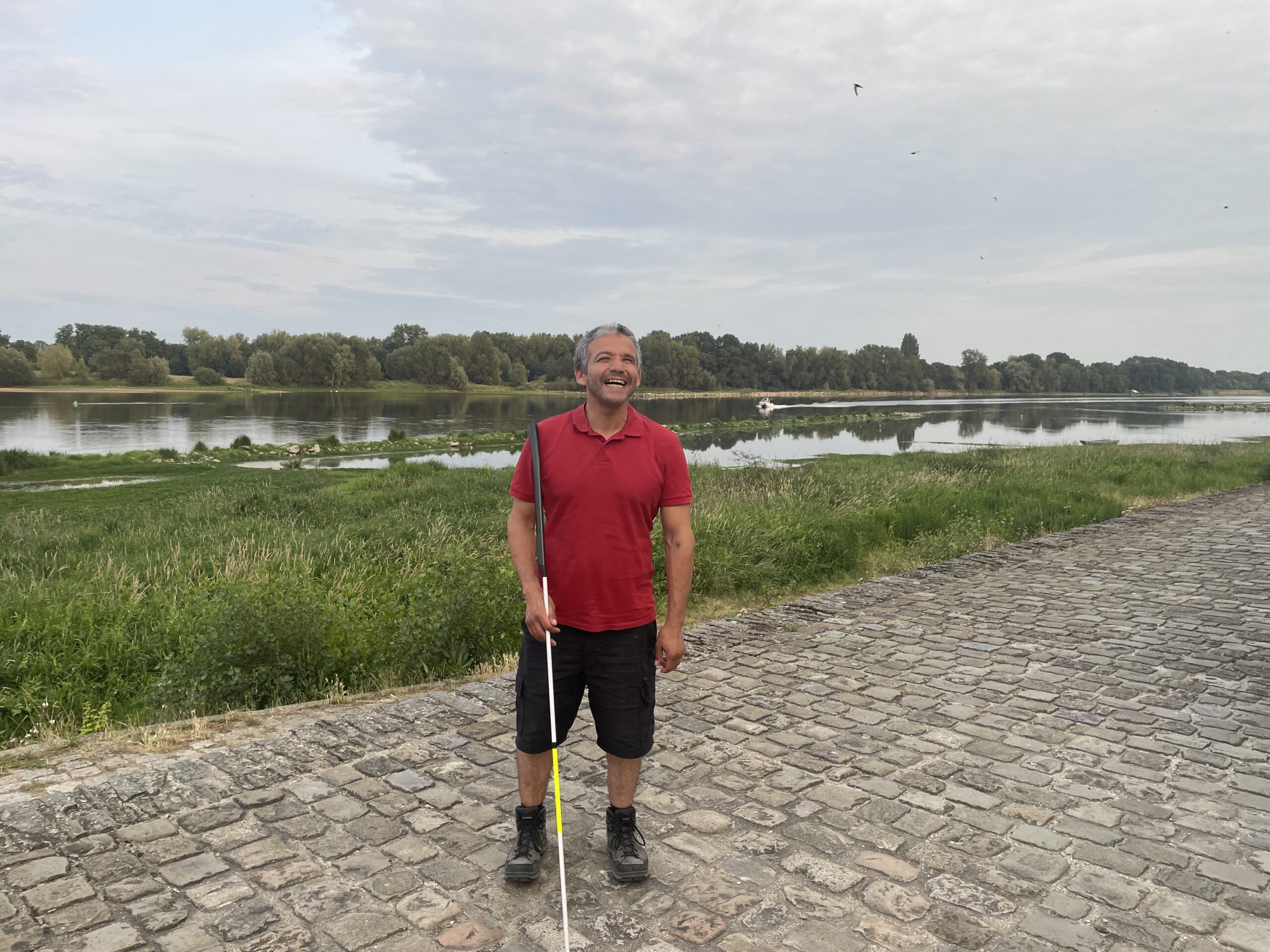 Juan standing on a pavement in France with water in the Background